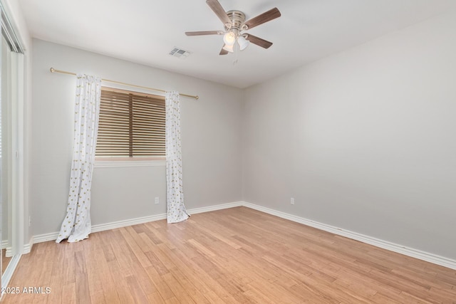 empty room featuring light wood-style floors, baseboards, ceiling fan, and visible vents