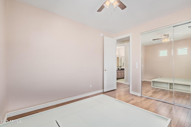 unfurnished bedroom with baseboards, ceiling fan, wood finished floors, and a closet