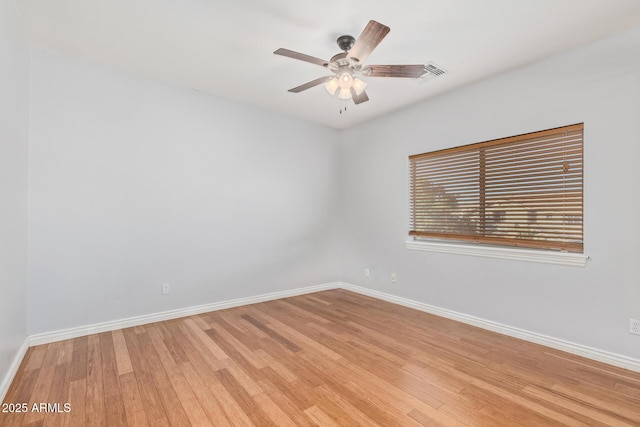 empty room with baseboards, a ceiling fan, and light wood-type flooring