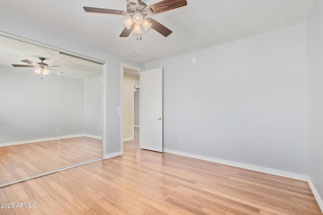 unfurnished bedroom featuring light wood-style floors, baseboards, ceiling fan, and a closet