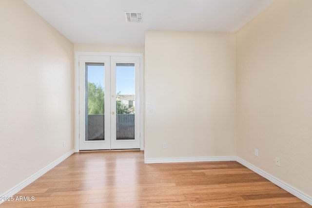 empty room featuring baseboards, french doors, light wood-type flooring, and visible vents