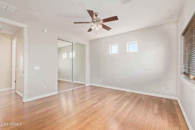 unfurnished bedroom with a ceiling fan, visible vents, light wood-type flooring, baseboards, and a closet