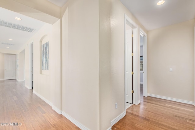 hallway with baseboards, light wood-type flooring, and visible vents