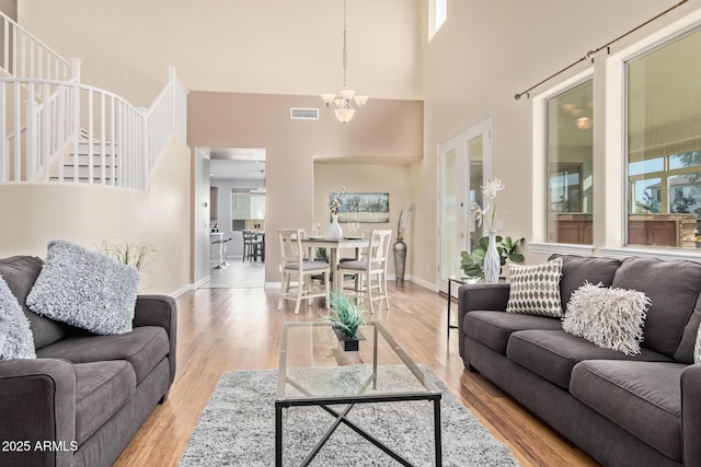 living area featuring a chandelier, visible vents, wood finished floors, and a towering ceiling