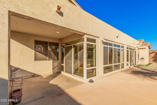 rear view of house with a patio and stucco siding