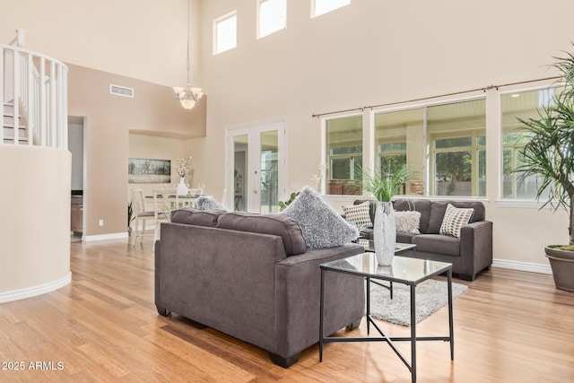 living area with baseboards, a high ceiling, light wood-type flooring, and visible vents