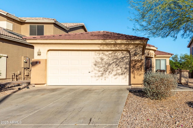 mediterranean / spanish home with a garage, a tiled roof, concrete driveway, and stucco siding