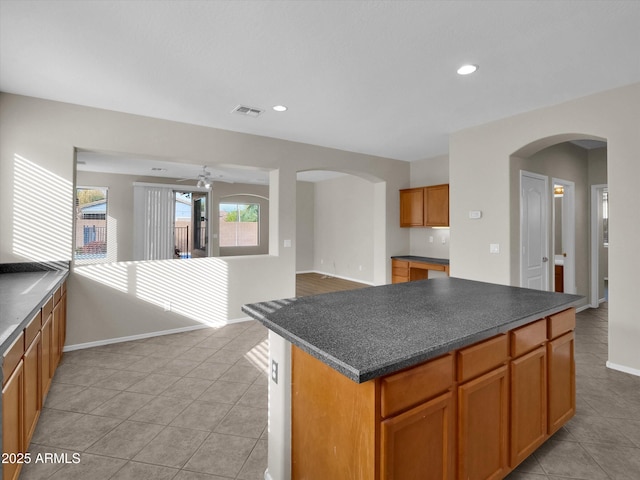 kitchen with light tile patterned floors, a center island, and ceiling fan