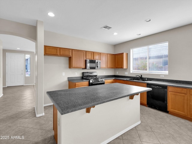 kitchen with a breakfast bar, black appliances, sink, light tile patterned floors, and a kitchen island