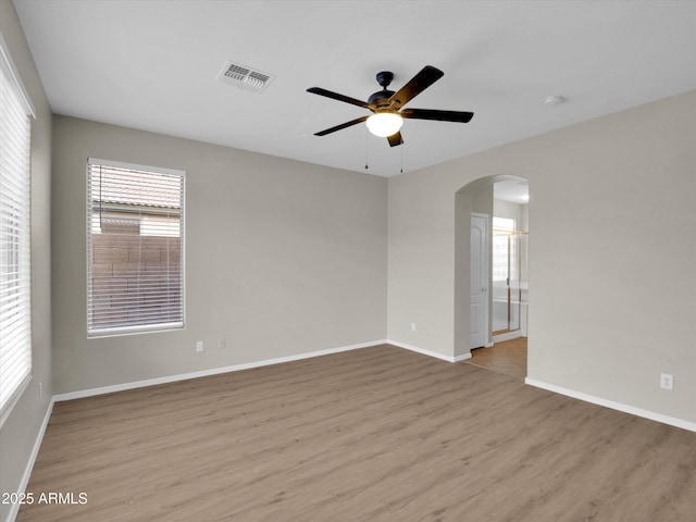 spare room with ceiling fan, light wood-type flooring, and a wealth of natural light