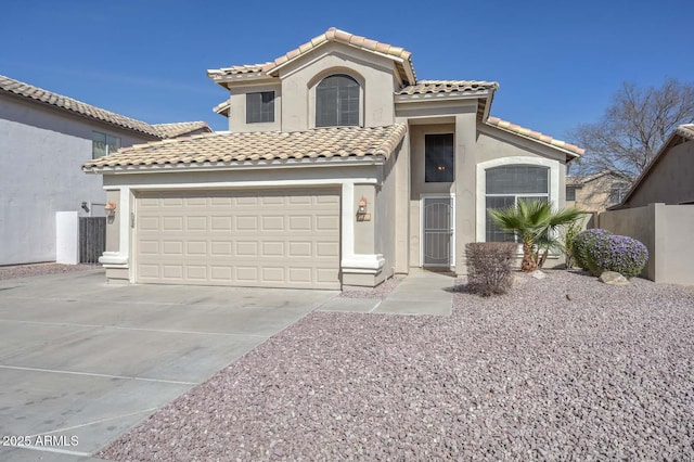 mediterranean / spanish-style home with driveway, a tiled roof, fence, and stucco siding