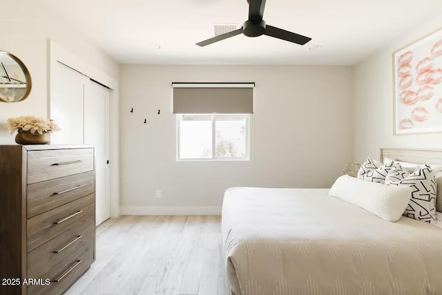 bedroom with light wood-type flooring, ceiling fan, and a closet