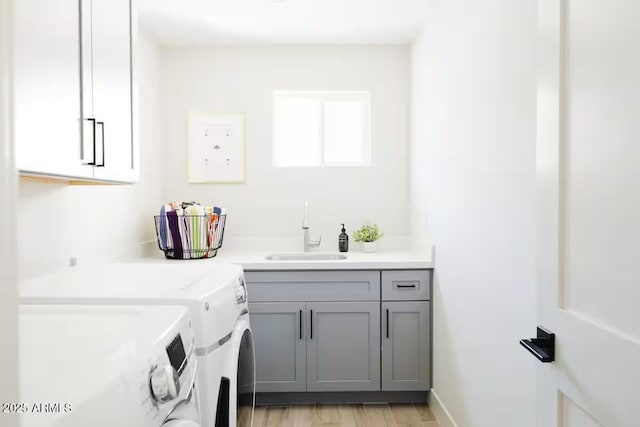 clothes washing area with light hardwood / wood-style flooring, sink, separate washer and dryer, and cabinets