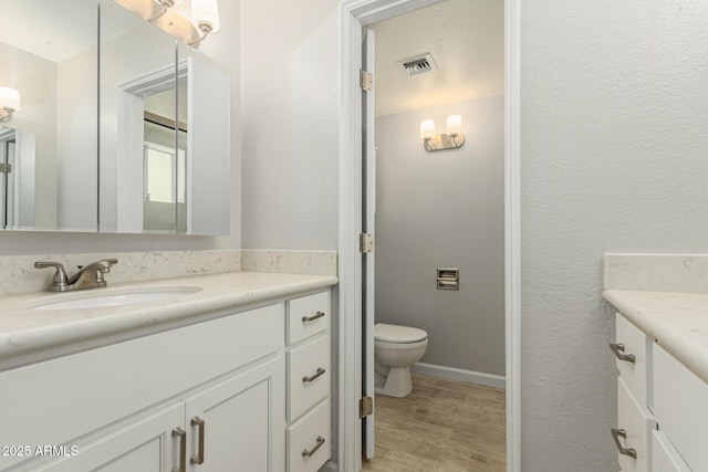 1240 E Indigo St, Mesa, AZ 85203 - bathroom featuring visible vents, vanity, a textured wall, wood finished floors, and toilet