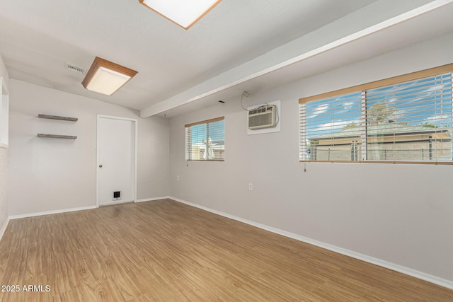 1240 E Indigo St, Mesa, AZ 85203 - spare room with visible vents, lofted ceiling, wood finished floors, baseboards, and a wall mounted air conditioner