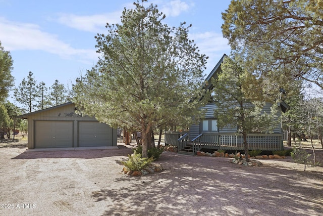 view of front of house with dirt driveway, an outbuilding, a wooden deck, and a garage