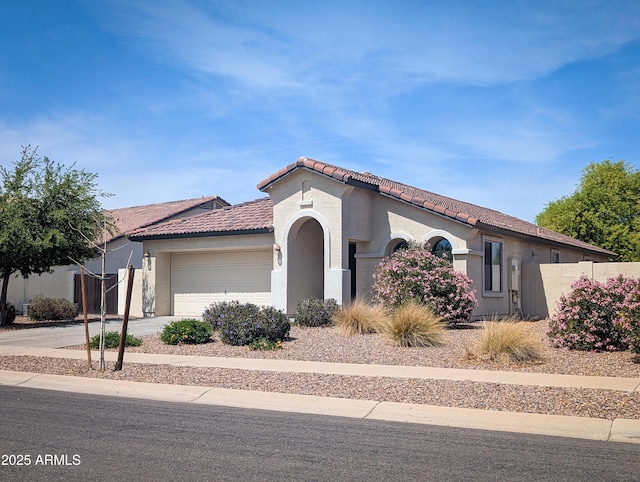 mediterranean / spanish-style home with a tiled roof, concrete driveway, fence, an attached garage, and stucco siding