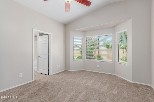 carpeted spare room featuring lofted ceiling, a ceiling fan, and baseboards