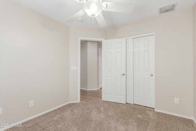 unfurnished bedroom featuring carpet flooring, baseboards, visible vents, a closet, and ceiling fan