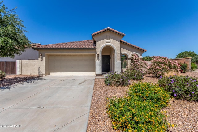 mediterranean / spanish house featuring an attached garage, a tiled roof, stucco siding, and driveway