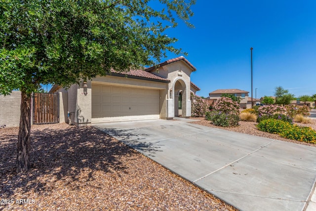mediterranean / spanish home with a tiled roof, a gate, driveway, an attached garage, and stucco siding