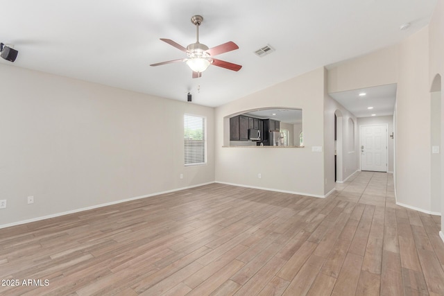 unfurnished living room featuring ceiling fan, lofted ceiling, visible vents, and light wood-style flooring