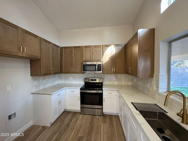 kitchen featuring sink, tasteful backsplash, dark hardwood / wood-style flooring, stainless steel appliances, and white cabinets