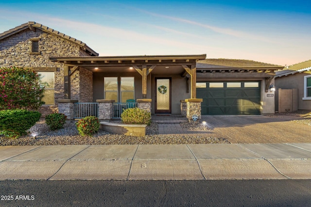 view of front of property featuring a porch, a garage, stone siding, decorative driveway, and stucco siding