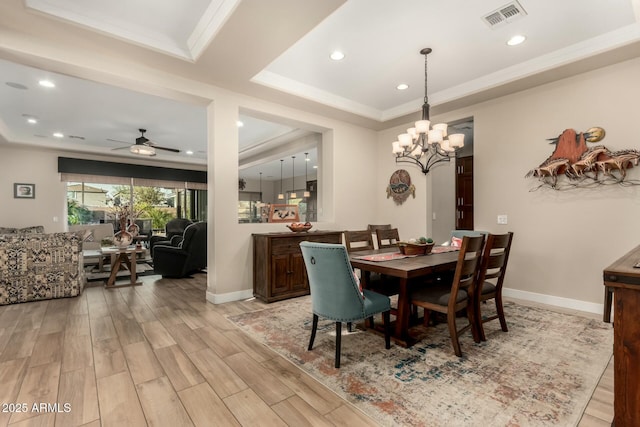 dining room with a ceiling fan, visible vents, baseboards, light wood finished floors, and a raised ceiling