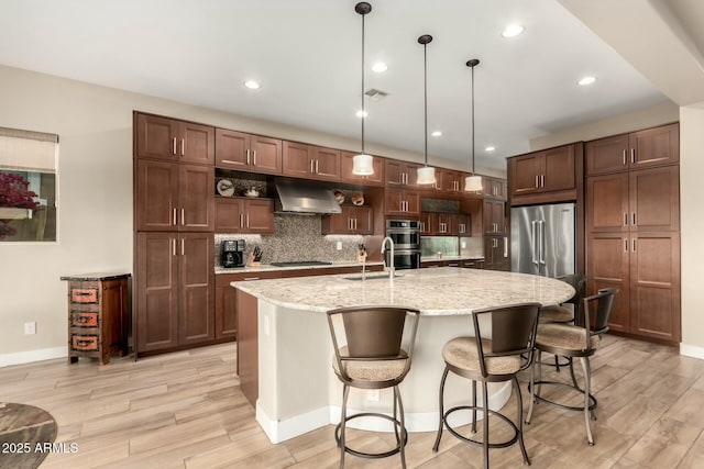 kitchen featuring under cabinet range hood, stainless steel appliances, visible vents, light wood-type flooring, and tasteful backsplash