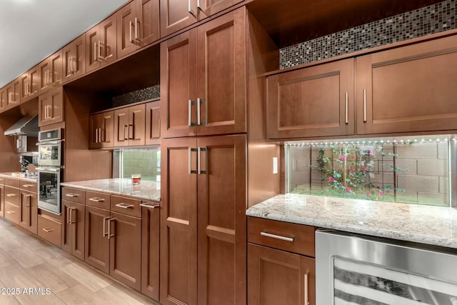 kitchen with wall chimney range hood, beverage cooler, decorative backsplash, and stainless steel double oven