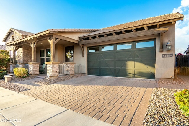 view of front of house featuring a porch, a garage, stone siding, decorative driveway, and stucco siding