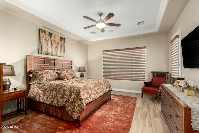 bedroom featuring a raised ceiling, visible vents, baseboards, and wood finished floors