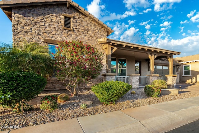 view of front facade featuring stone siding, a porch, and stucco siding