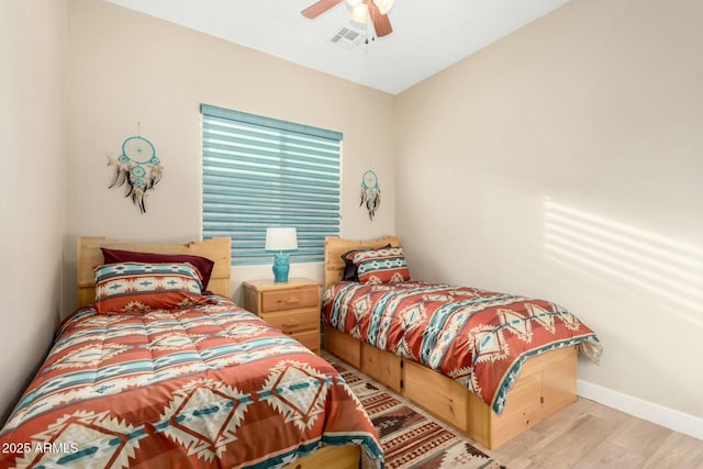 bedroom featuring a ceiling fan, baseboards, visible vents, and wood finished floors