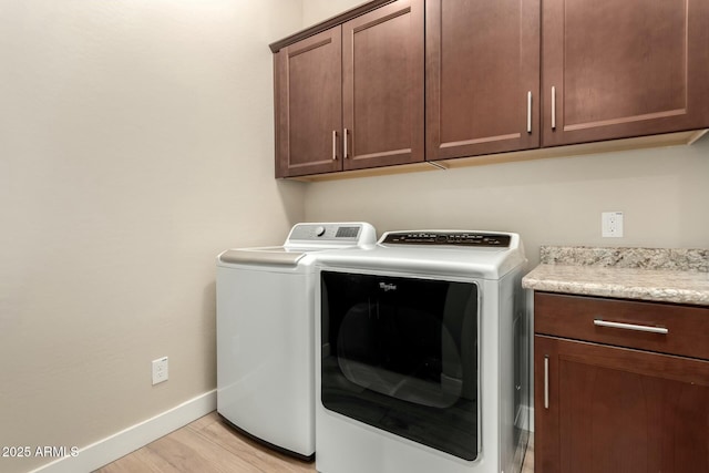 laundry room with light wood finished floors, independent washer and dryer, cabinet space, and baseboards