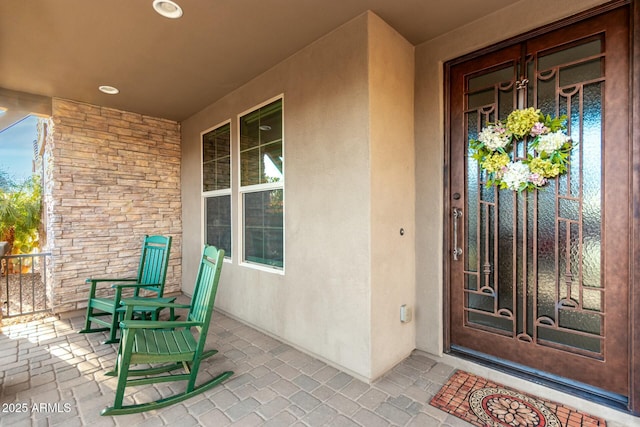 entrance to property featuring a porch and stucco siding