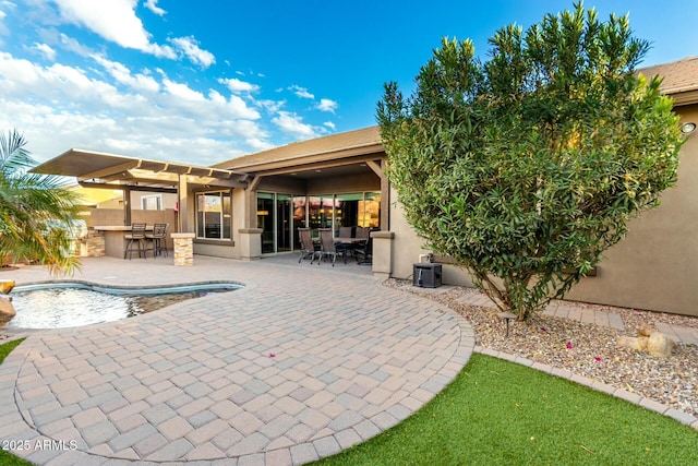 back of property featuring outdoor dry bar, a patio area, and stucco siding