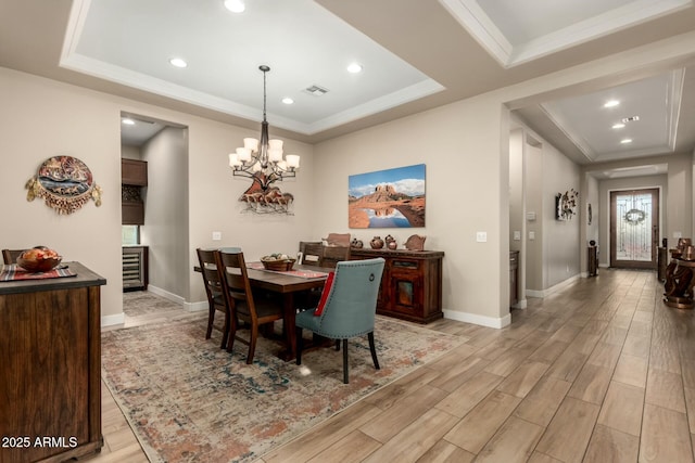 dining area with light wood-style floors, visible vents, and a tray ceiling