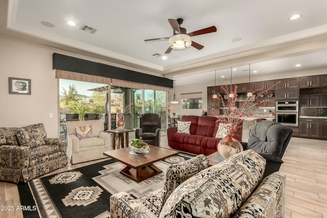 living area with recessed lighting, a raised ceiling, visible vents, and light wood-style floors