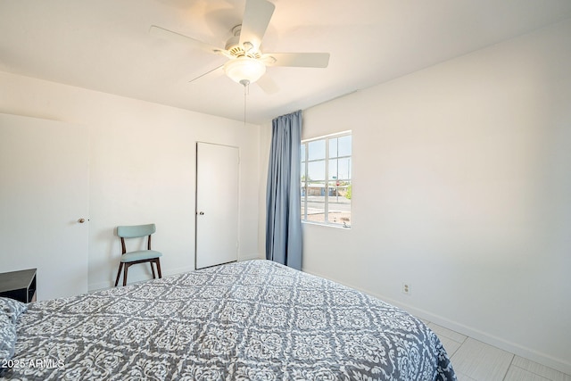 tiled bedroom featuring baseboards and ceiling fan