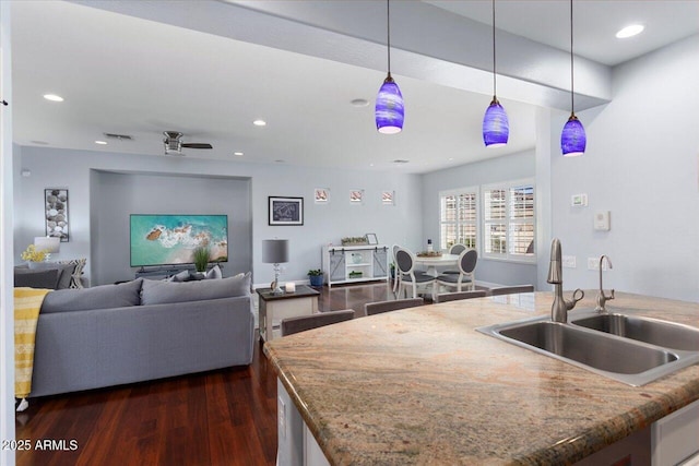 kitchen with dark wood-type flooring, ceiling fan, pendant lighting, and sink