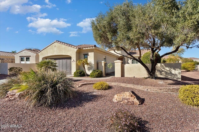 mediterranean / spanish house with a fenced front yard, stucco siding, an attached garage, a gate, and a tiled roof