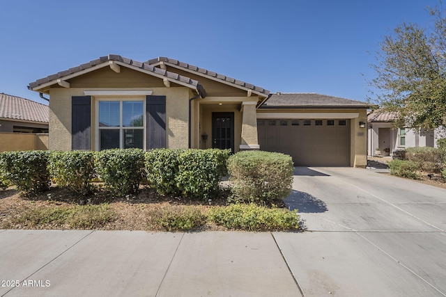 view of front of home with driveway, a tiled roof, a garage, and stucco siding