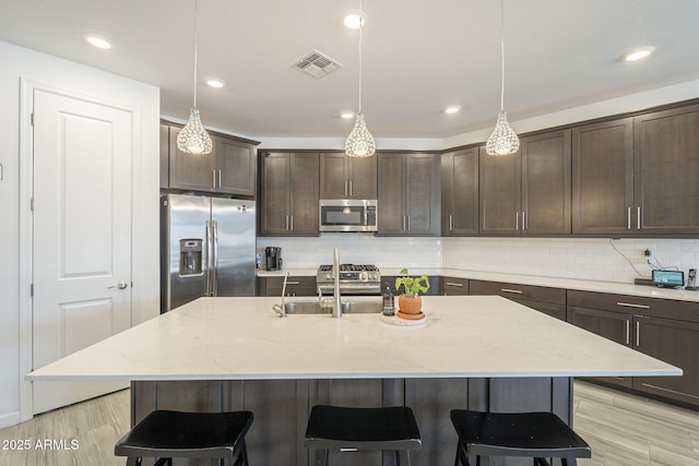 kitchen featuring appliances with stainless steel finishes, a breakfast bar area, visible vents, and dark brown cabinetry