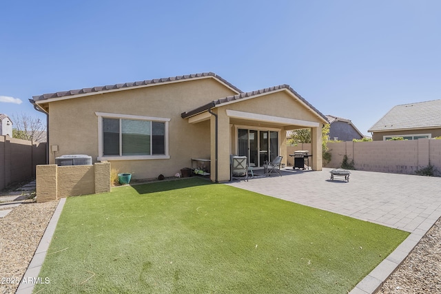 rear view of property featuring a yard, a fenced backyard, a patio, and stucco siding