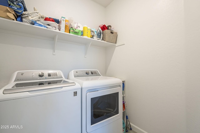 clothes washing area with laundry area, washing machine and dryer, and baseboards