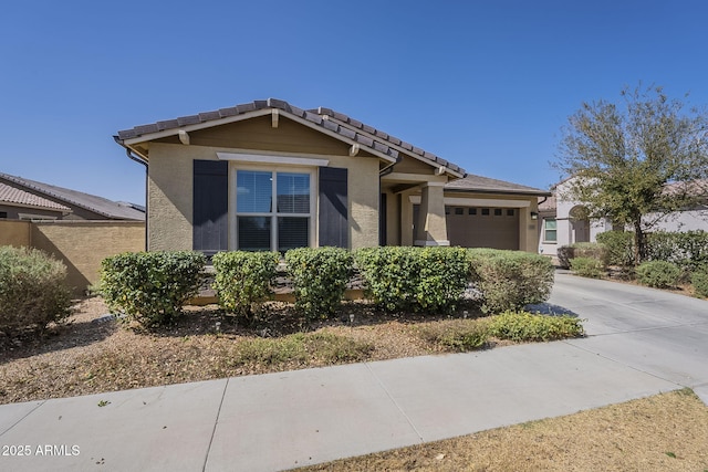 craftsman inspired home with a garage, a tile roof, concrete driveway, and stucco siding