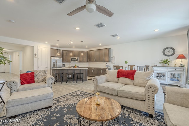 living area with light wood finished floors, visible vents, and recessed lighting