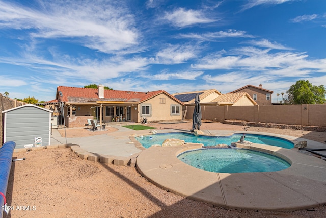 view of swimming pool with an in ground hot tub, a storage shed, and a patio area